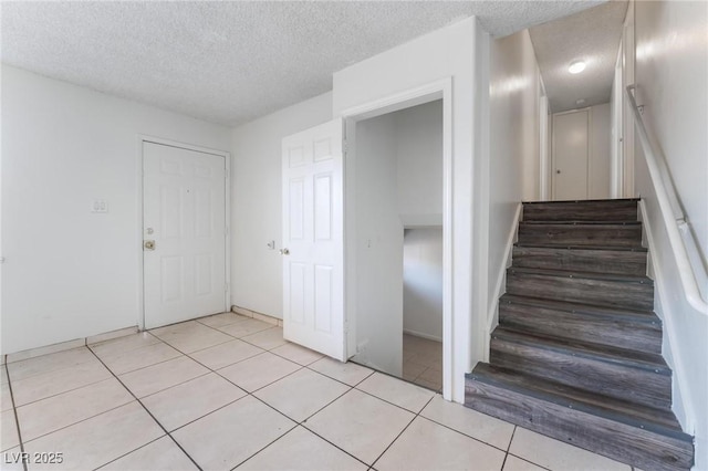 stairs with tile patterned flooring and a textured ceiling