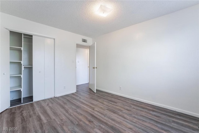 unfurnished bedroom with dark hardwood / wood-style flooring, a closet, and a textured ceiling