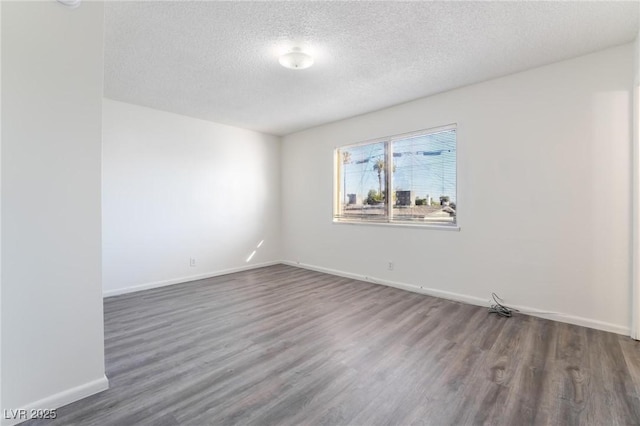 spare room with dark hardwood / wood-style floors and a textured ceiling