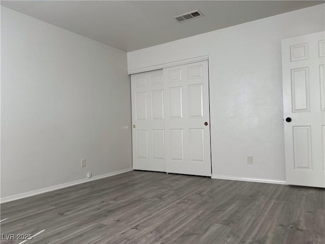 unfurnished bedroom featuring dark hardwood / wood-style flooring and a closet