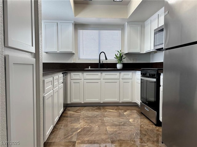 kitchen featuring white cabinetry, stainless steel appliances, a tray ceiling, and sink