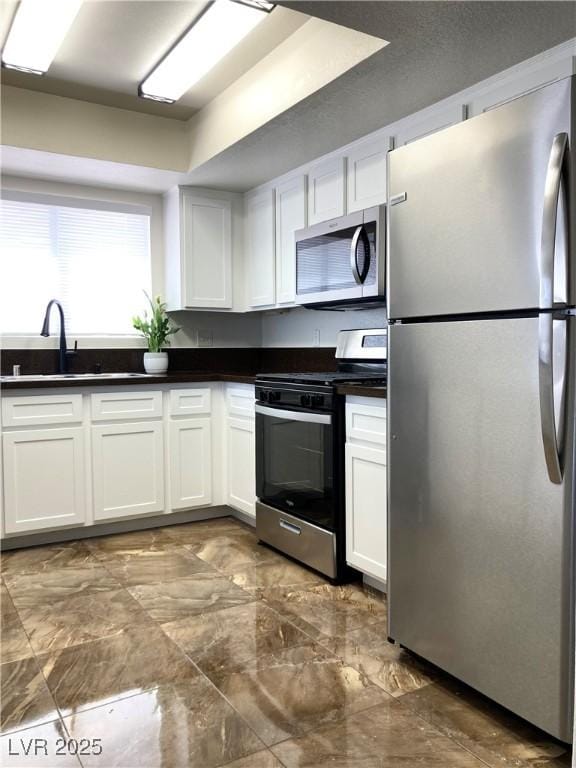 kitchen with appliances with stainless steel finishes, sink, and white cabinets