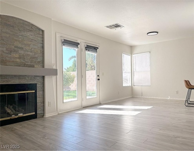 unfurnished living room with light hardwood / wood-style flooring and a textured ceiling