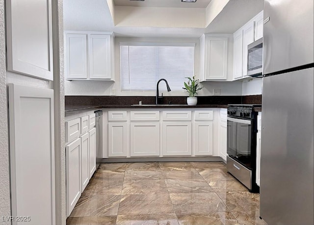 kitchen featuring white cabinetry, sink, stainless steel appliances, and dark stone countertops