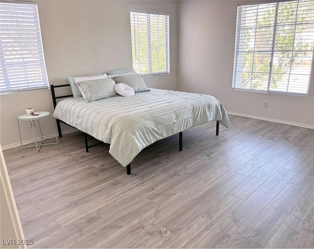 bedroom with multiple windows and light wood-type flooring