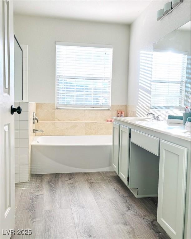 bathroom with hardwood / wood-style floors, vanity, a washtub, and tile walls