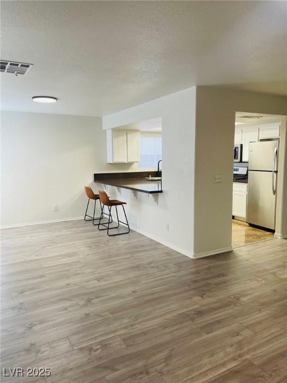 interior space featuring sink, a textured ceiling, and light wood-type flooring