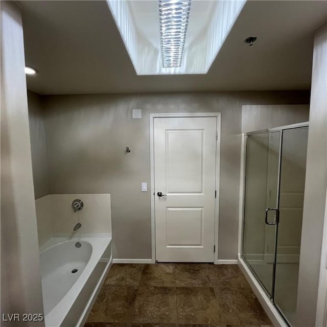 bathroom featuring a stall shower, a garden tub, and baseboards