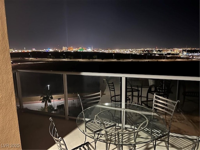 patio at twilight featuring outdoor dining space and a view of city lights