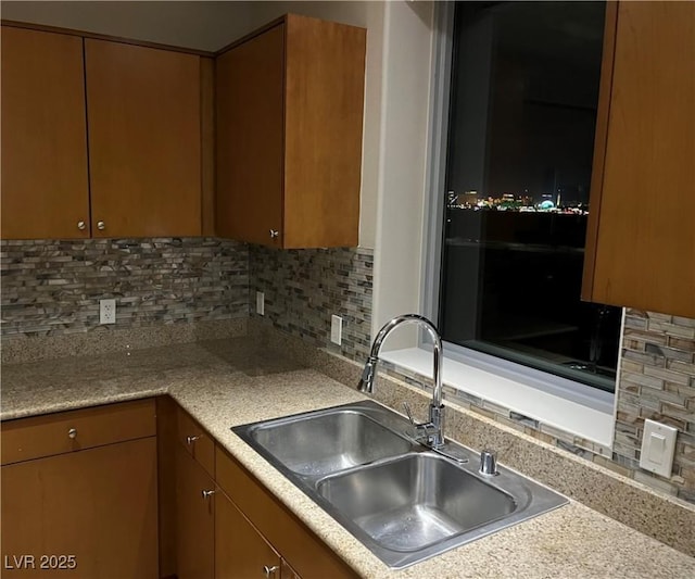 kitchen with tasteful backsplash, brown cabinets, light countertops, and a sink