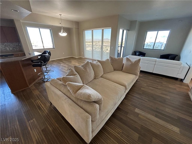 living area with dark wood-type flooring, a wealth of natural light, and baseboards