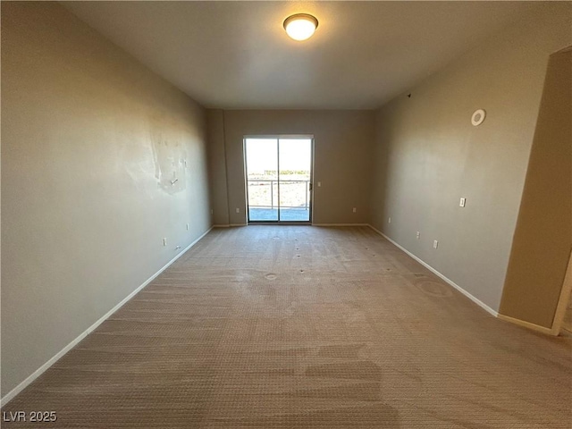 empty room featuring light colored carpet and baseboards