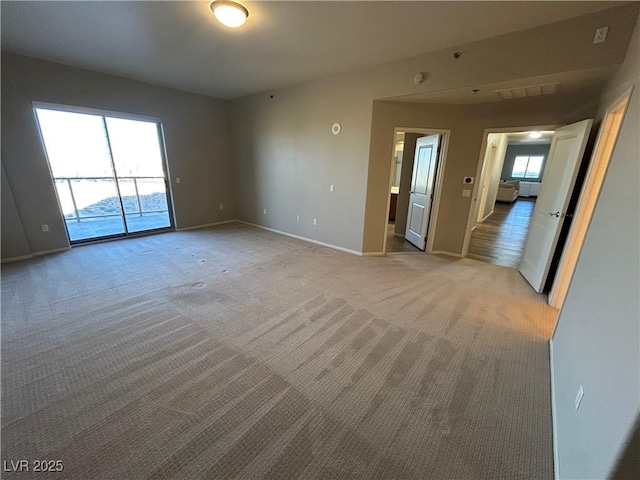 unfurnished room with light carpet and baseboards