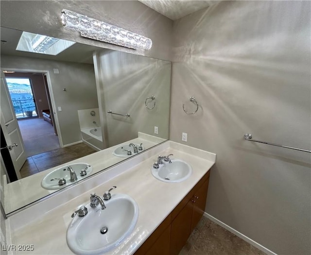 bathroom featuring double vanity, a skylight, and a sink