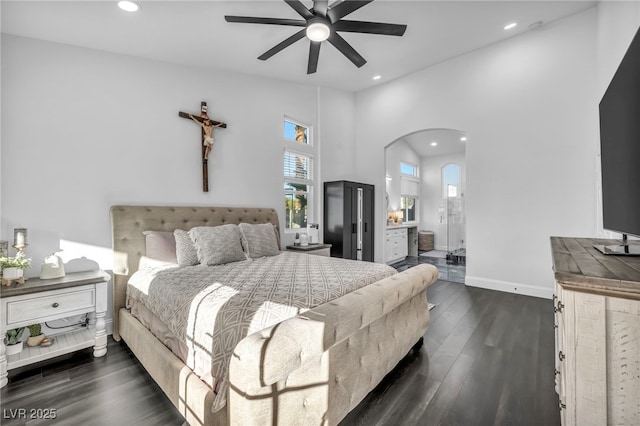 bedroom featuring dark wood-type flooring, ensuite bath, ceiling fan, and vaulted ceiling