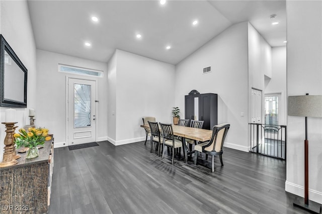 dining room with dark wood-type flooring and high vaulted ceiling