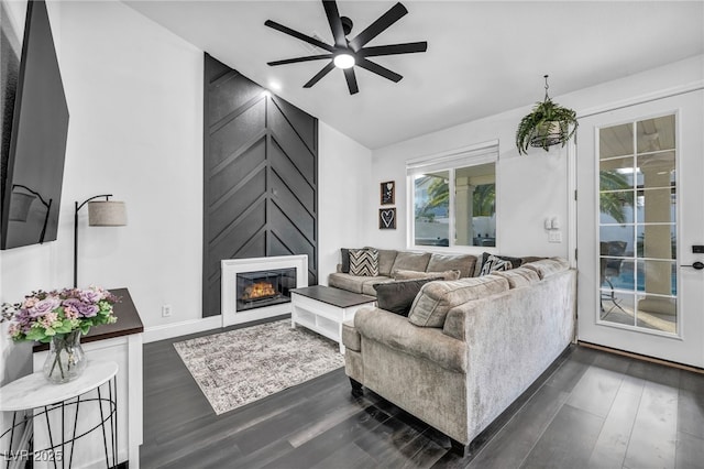 living room with ceiling fan, a large fireplace, lofted ceiling, and dark hardwood / wood-style flooring