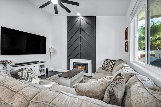 living room featuring hardwood / wood-style flooring, ceiling fan, and a fireplace