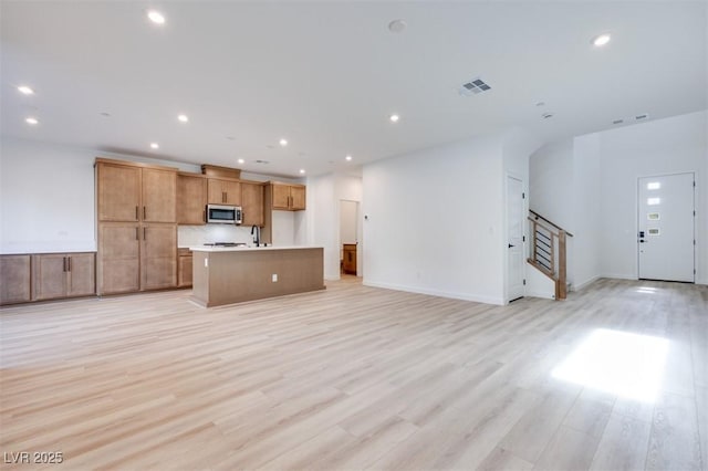 unfurnished living room featuring sink and light hardwood / wood-style floors