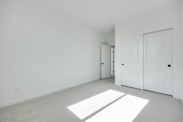 unfurnished bedroom with light colored carpet and a closet