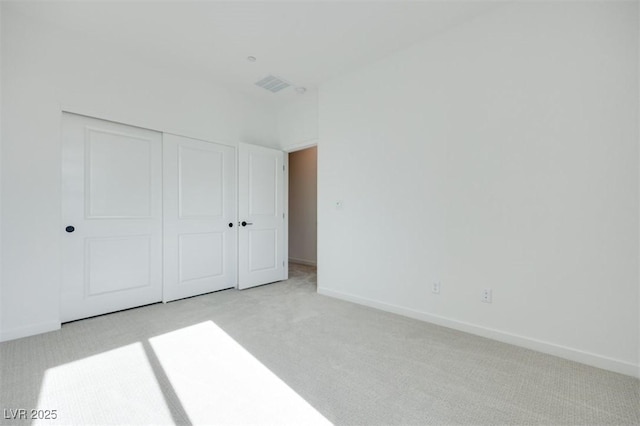 unfurnished bedroom featuring a closet and light carpet