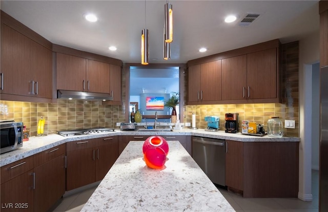 kitchen with tasteful backsplash, visible vents, stainless steel appliances, under cabinet range hood, and a sink