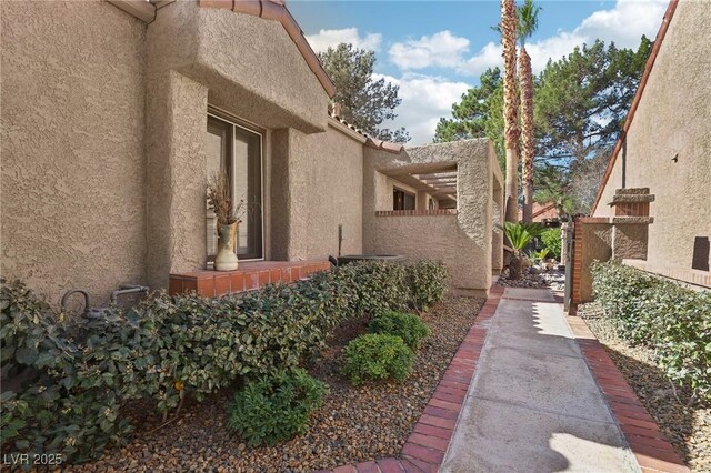 view of side of home with a tile roof, fence, and stucco siding