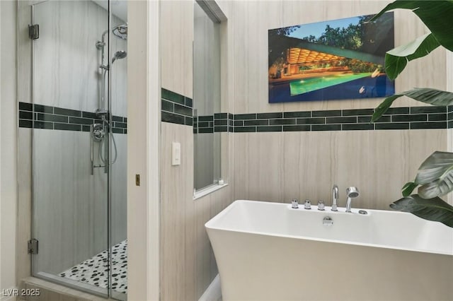 full bath with tile walls, a soaking tub, and a shower stall