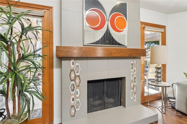 interior details featuring a tile fireplace and wood finished floors