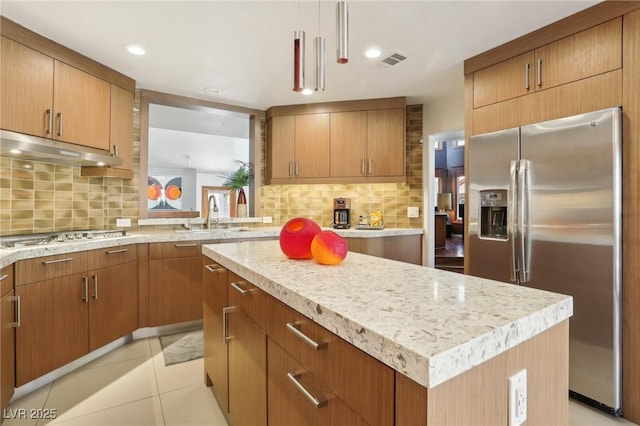 kitchen featuring a center island, visible vents, appliances with stainless steel finishes, a sink, and under cabinet range hood