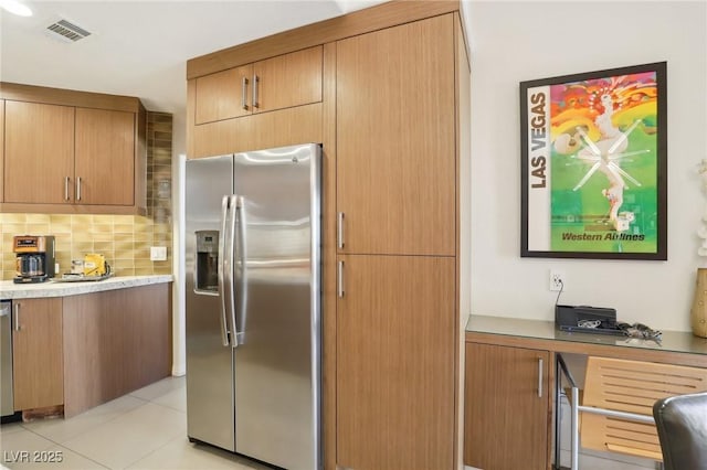 kitchen featuring light tile patterned floors, stainless steel appliances, light countertops, visible vents, and decorative backsplash