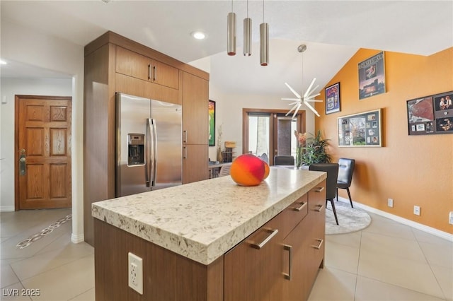 kitchen featuring a kitchen island, baseboards, vaulted ceiling, stainless steel fridge, and decorative light fixtures