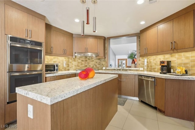 kitchen featuring under cabinet range hood, a kitchen island, stainless steel appliances, and decorative backsplash