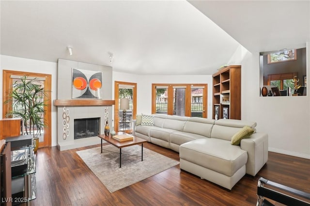 living room featuring lofted ceiling, a large fireplace, baseboards, and wood finished floors