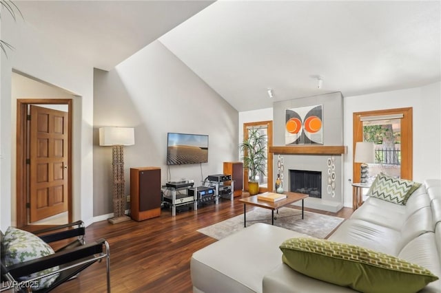 living room with vaulted ceiling, a tile fireplace, wood finished floors, and baseboards