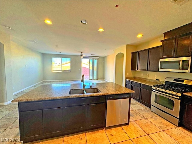 kitchen featuring a center island with sink, sink, dark brown cabinets, appliances with stainless steel finishes, and light tile patterned flooring