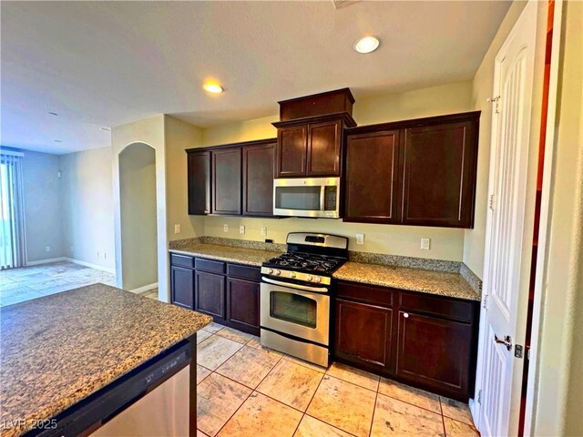 kitchen with light tile patterned floors, stainless steel appliances, and dark brown cabinetry