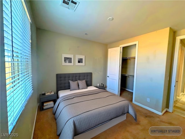 bedroom featuring a closet, a walk in closet, and light colored carpet