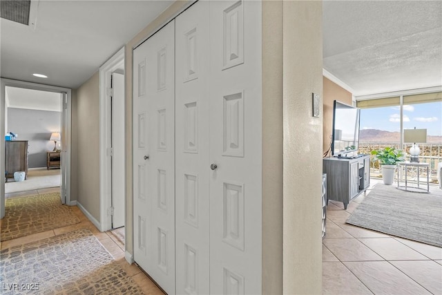 3111 Bel Air Dr Unit 20D, Las Vegas, NV 89109 - hallway with light tile patterned floors, a wall of windows, and a textured ceiling