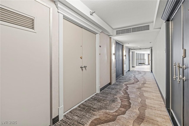 hall with a textured ceiling and carpet