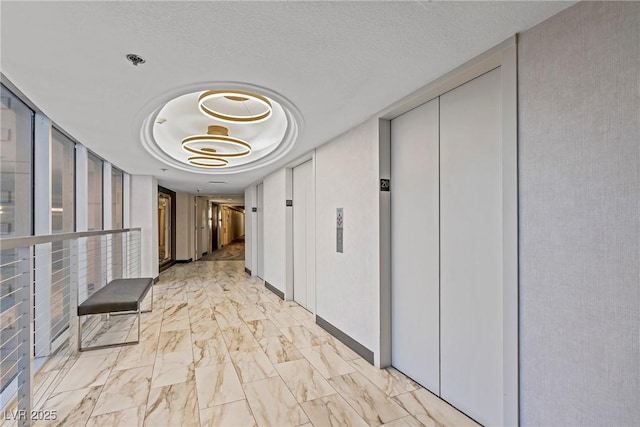 corridor featuring elevator and a textured ceiling