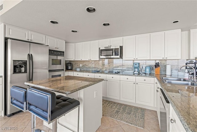 kitchen with light stone counters, a breakfast bar, a center island, and appliances with stainless steel finishes
