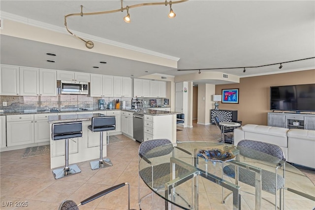 kitchen with stainless steel appliances, white cabinetry, a breakfast bar area, and decorative backsplash