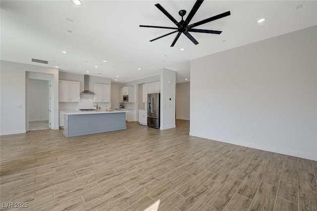 unfurnished living room featuring ceiling fan and light hardwood / wood-style floors