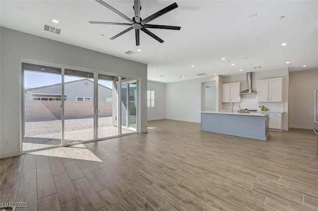 unfurnished living room with sink, ceiling fan, and light hardwood / wood-style flooring