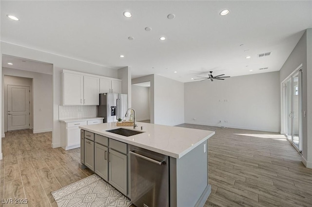 kitchen featuring a kitchen island with sink, sink, stainless steel appliances, and light hardwood / wood-style floors