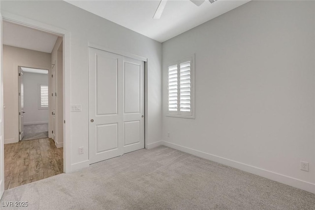 unfurnished bedroom with light colored carpet, a closet, and ceiling fan