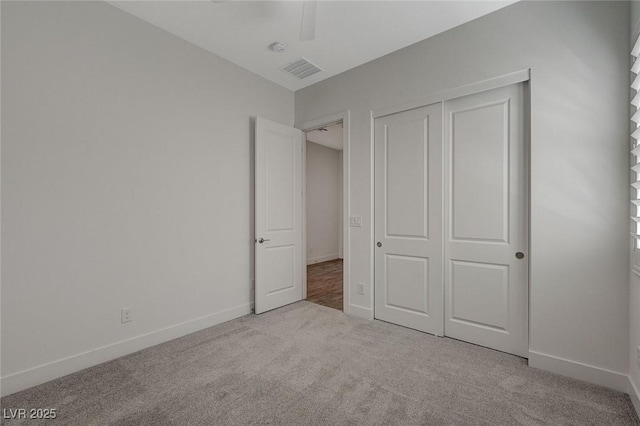 unfurnished bedroom with light colored carpet, a closet, and ceiling fan