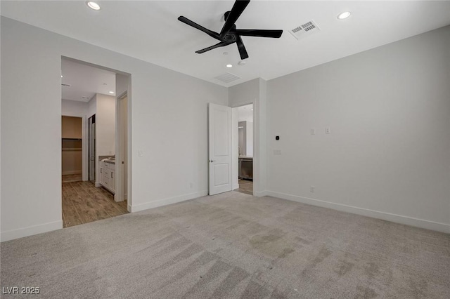 unfurnished bedroom with ensuite bathroom, light carpet, and ceiling fan