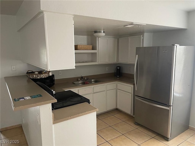 kitchen featuring stainless steel refrigerator, white cabinetry, sink, light tile patterned floors, and kitchen peninsula